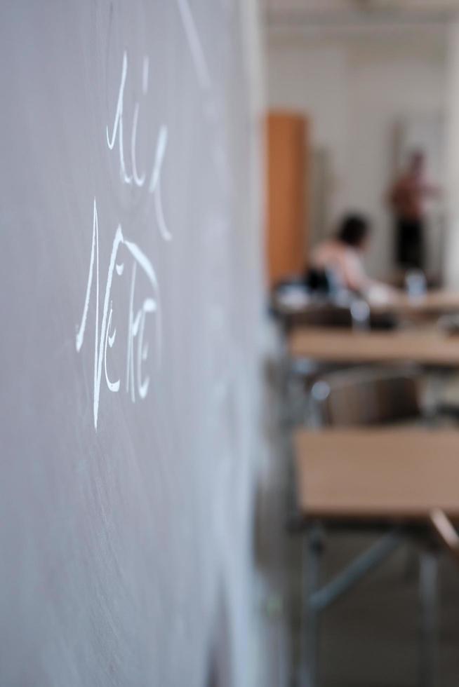 Blackboard with inscriptions made in white chalk, in a classroom. Education concept. photo