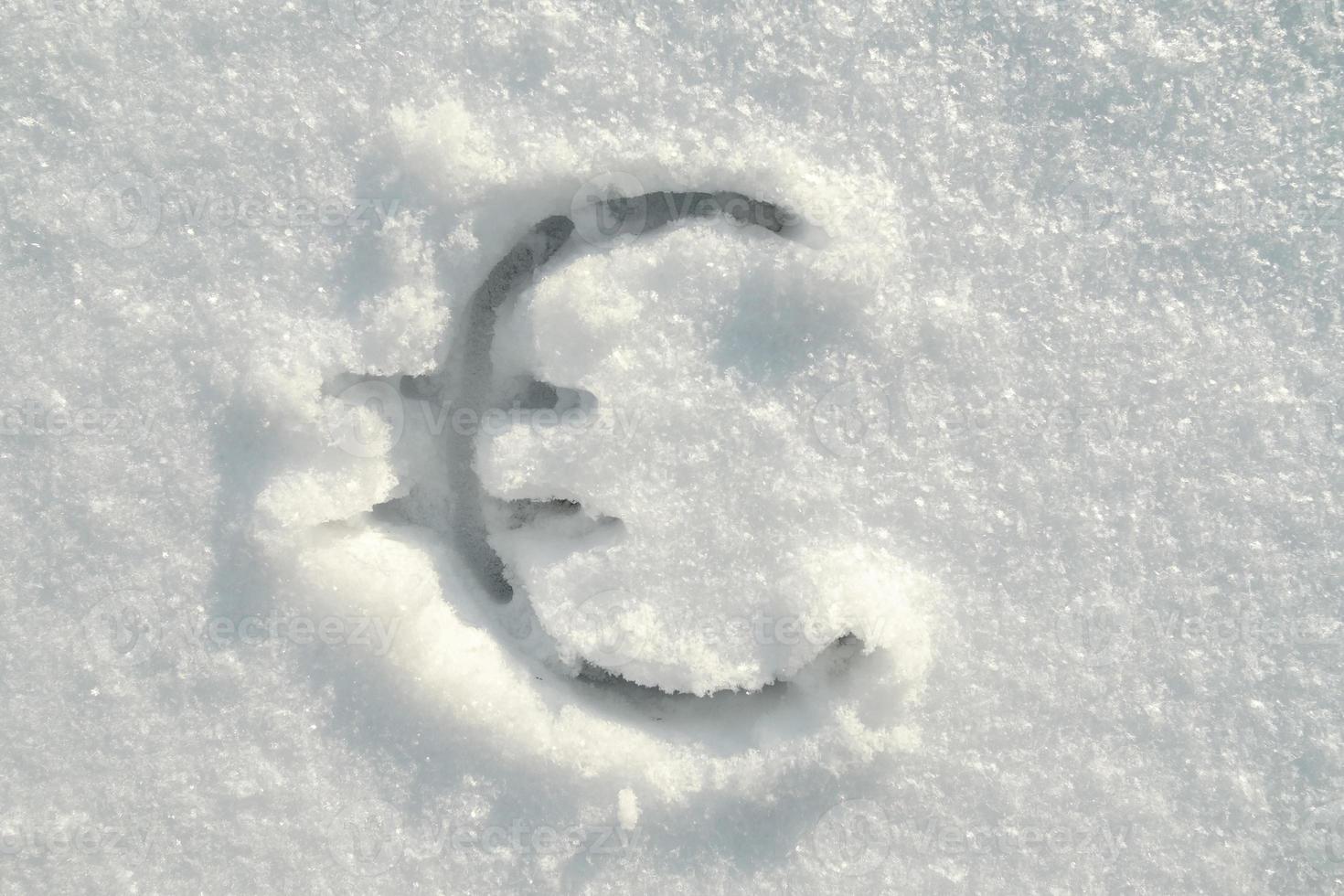 Euro sign written in pure snow on a sunny winter day. Top view. photo