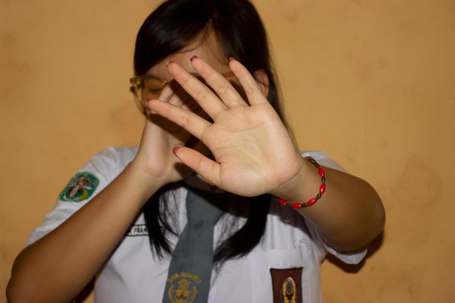 las manos de una mujer en un uniforme de escuela secundaria concepto de detener el acoso escolar. foto