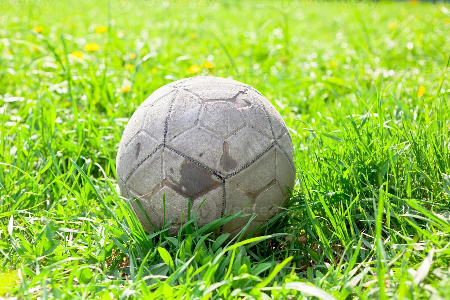 Old soccer ball on the green grass photo
