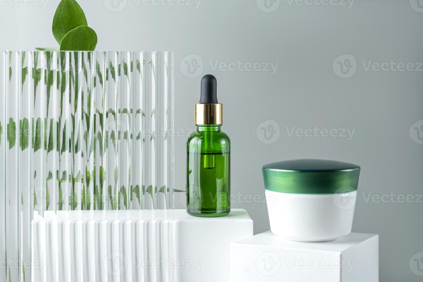 suero facial de colágeno antienvejecimiento en botella de vidrio verde y crema facial en podio blanco con espacio de copia. concepto de belleza cosmética orgánica natural. foto