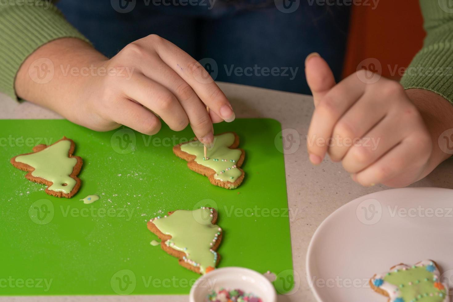 Girl decorates gingerbreads with sugar icing. Merry Christmas and happy new year concept photo