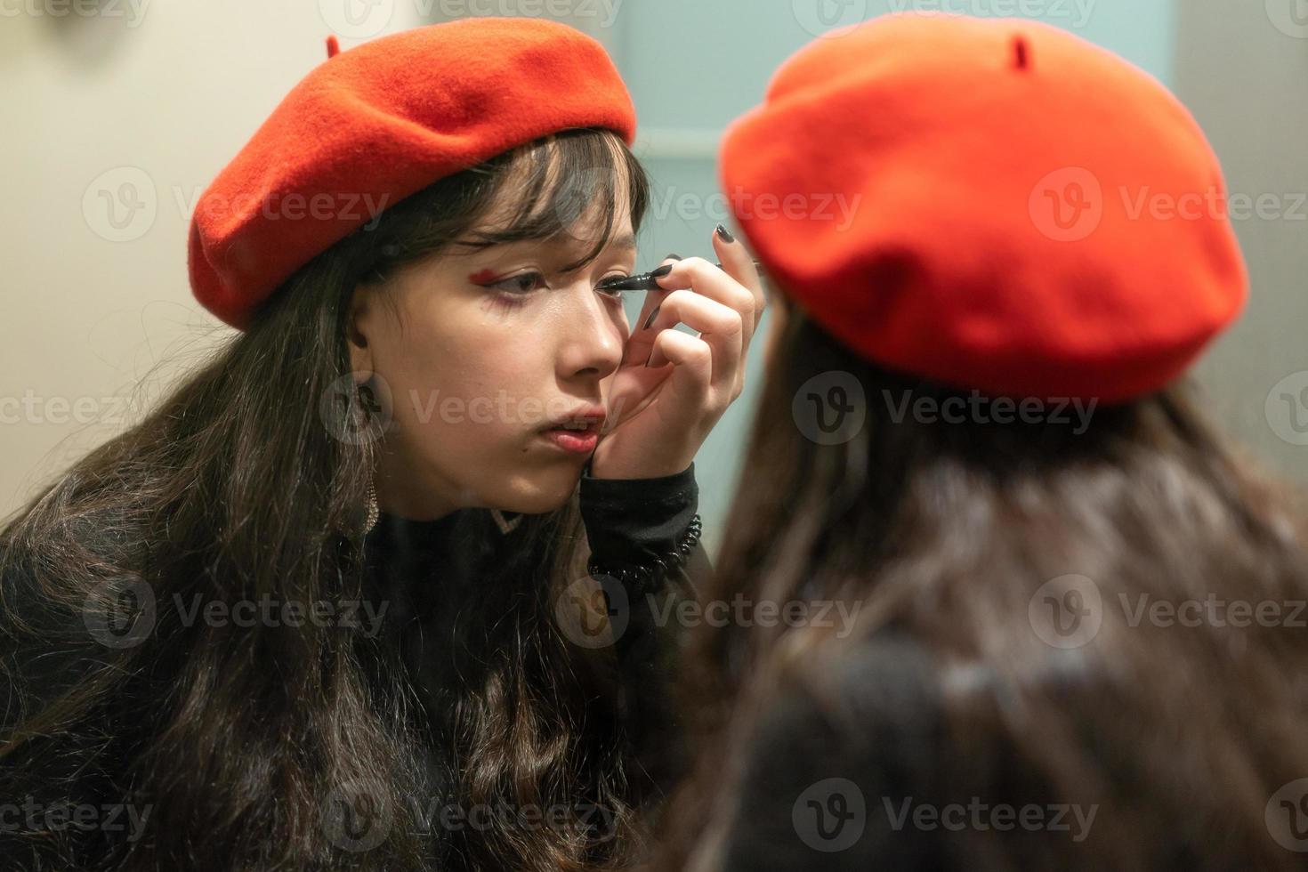 joven elegante haciendo su maquillaje con delineador de ojos foto