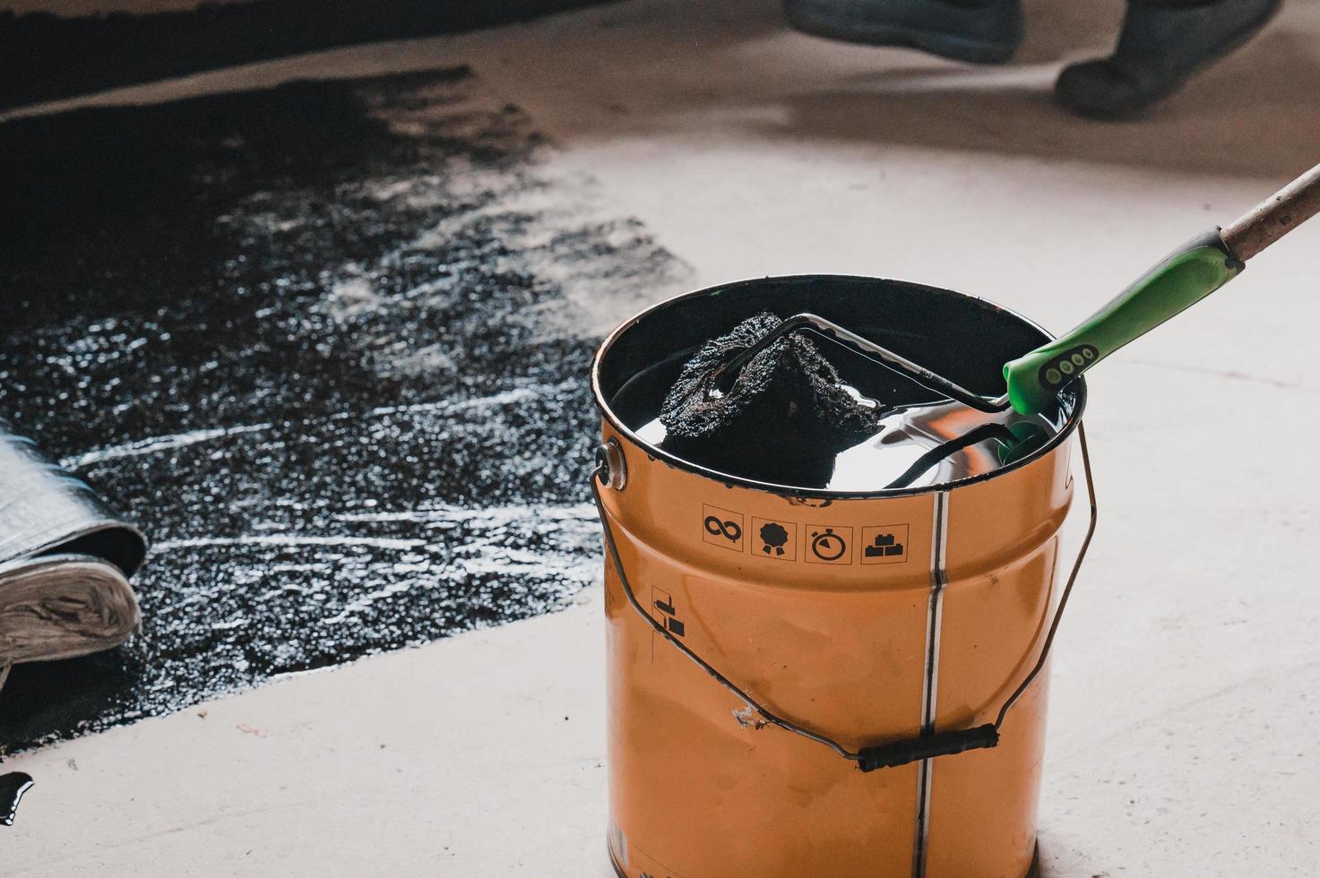 Applying hot resin to the floor for waterproofing, roller and bucket of resin. photo