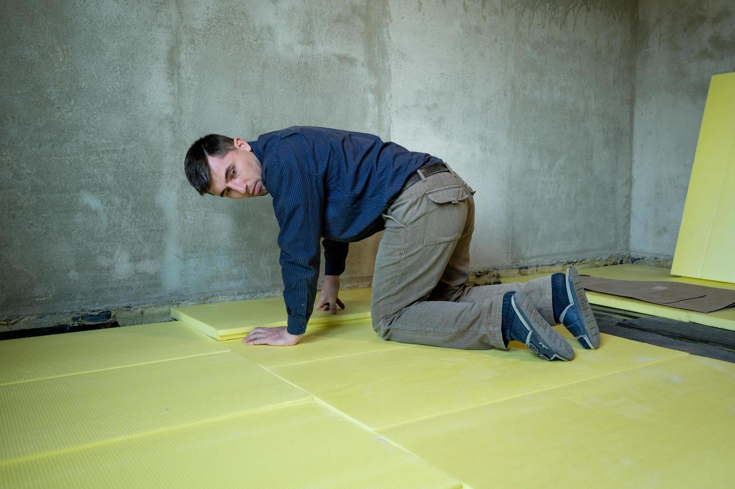 Installation of expanded polystyrene in the room for floor insulation, repair work alone, yellow expanded polystyrene. photo