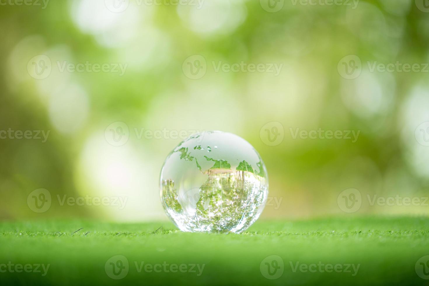 Close up of crystal globe resting on grass in a forest - environment concept. environmental, social, and governance in sustainable and ethical business on green background. photo