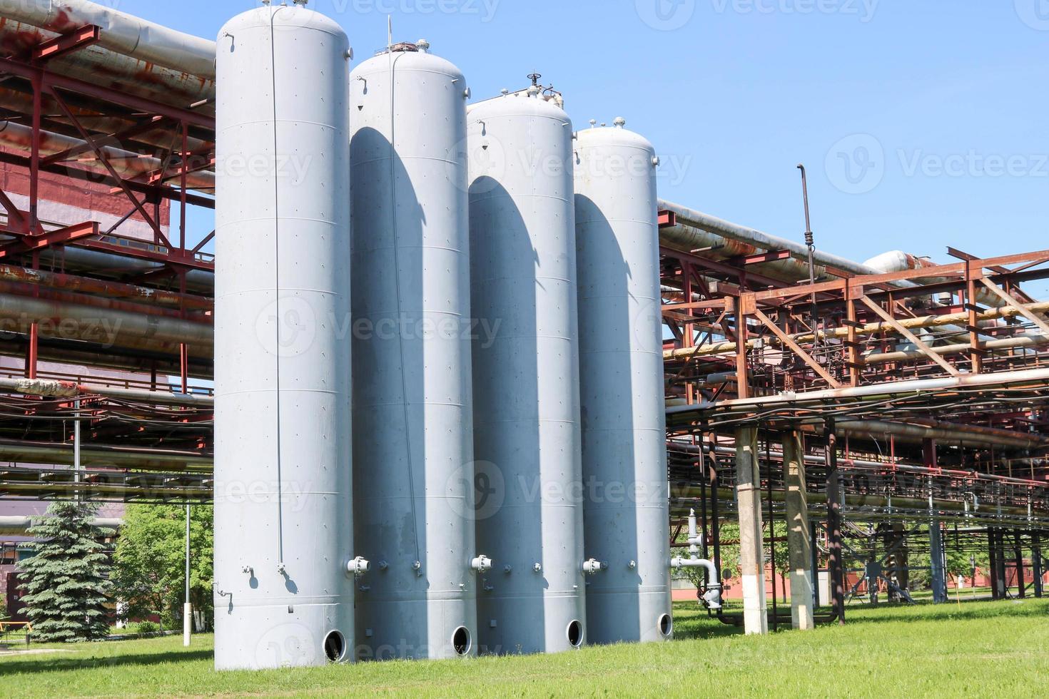 A large concrete technological industrial installation at a chemical petrochemical refinery with capacitive pipes by pumps compressors heat exchangers by pipelines and buildings photo