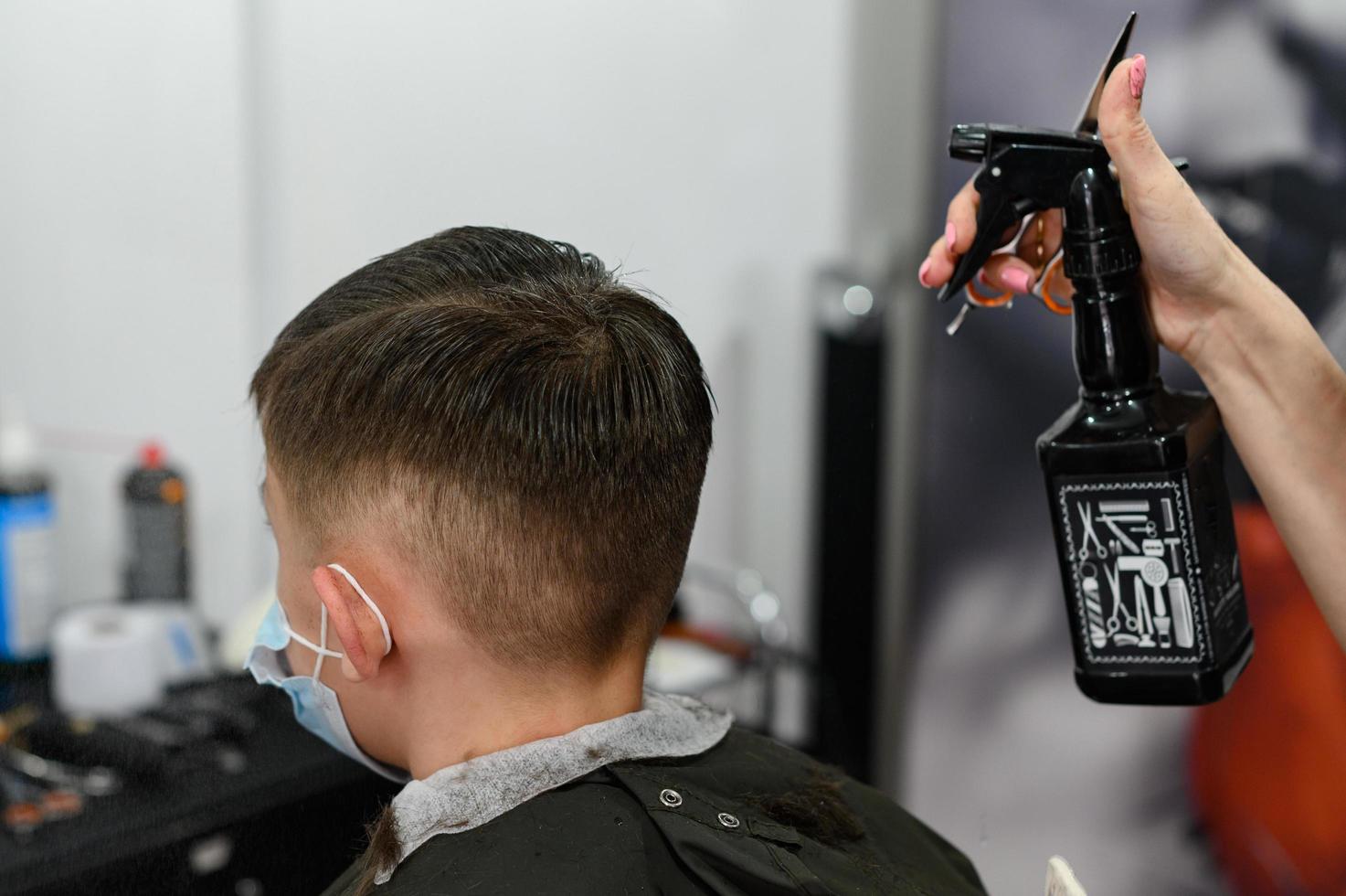 un adolescente en un salón de belleza se corta el pelo, un peluquero le corta el pelo a un adolescente. foto