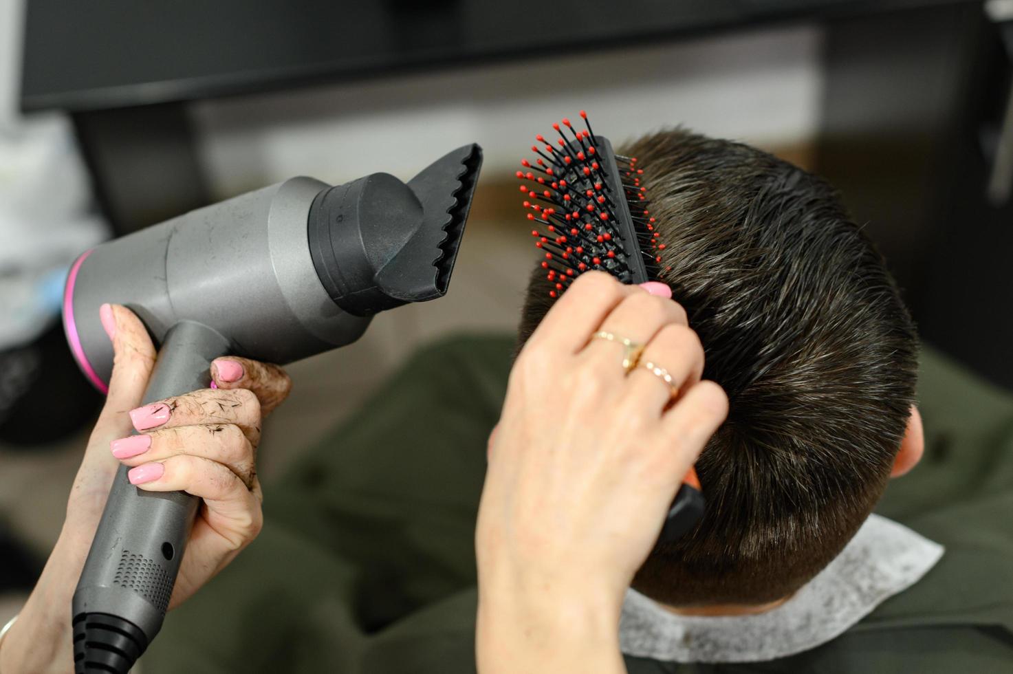 un adolescente se corta el pelo durante una pandemia en la barbería, se corta el pelo y se seca el pelo después de un corte de pelo. foto