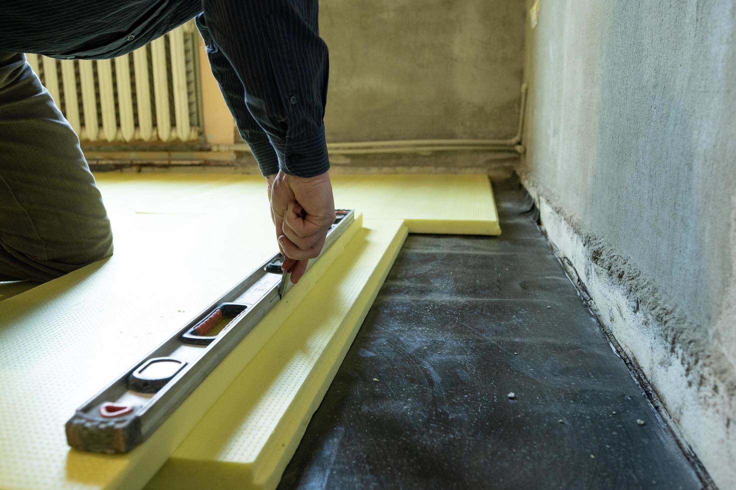 Close-up of the master cuts the size of expanded polystyrene on the floor, the process of floor insulation in the house. photo