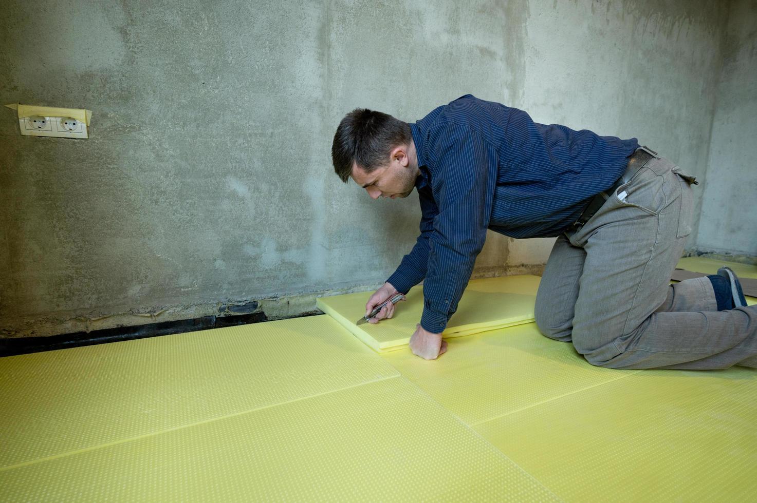 Close-up of the master cuts the size of expanded polystyrene on the floor, the process of floor insulation in the house. photo