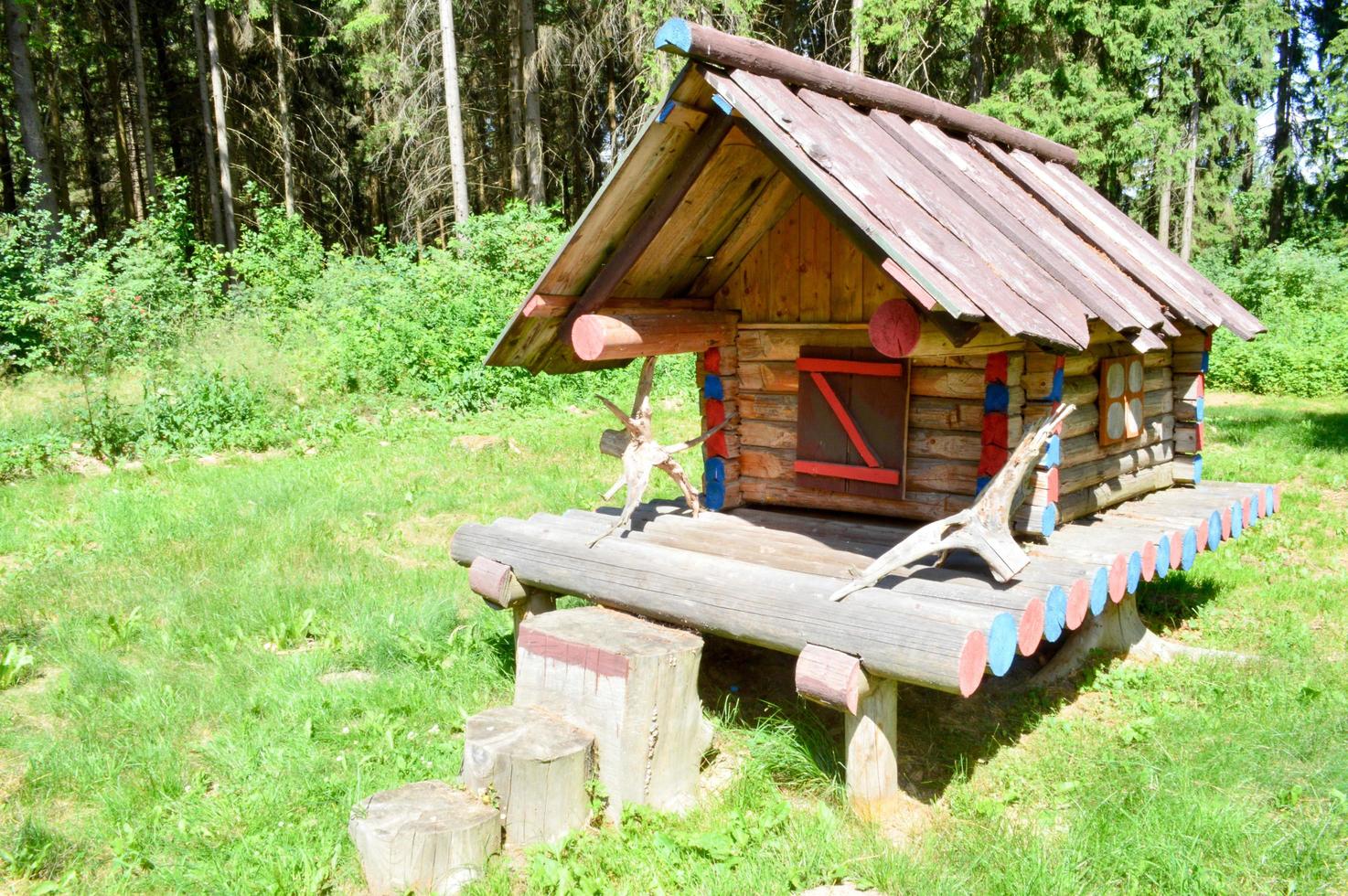 Small wooden ramshackle old hut house in a forest of logs of planks on the background of trees photo