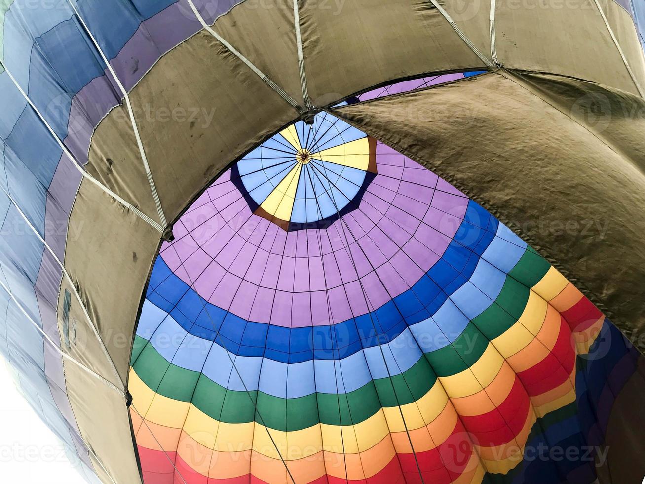 The texture, the view from the inside of the dome is a large multi-colored bright round iridescent colored striped flying balloon. The background photo