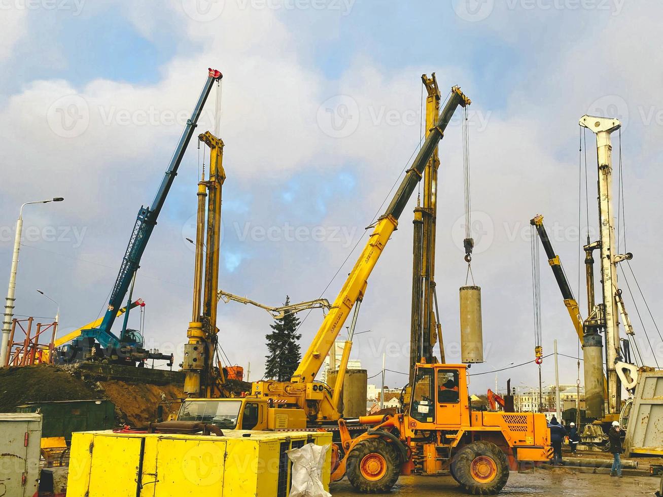 construction equipment at the overpass repair site. a tall, yellow crane with large wheels carries a round concrete block, a pile for the construction of a huge overpass photo