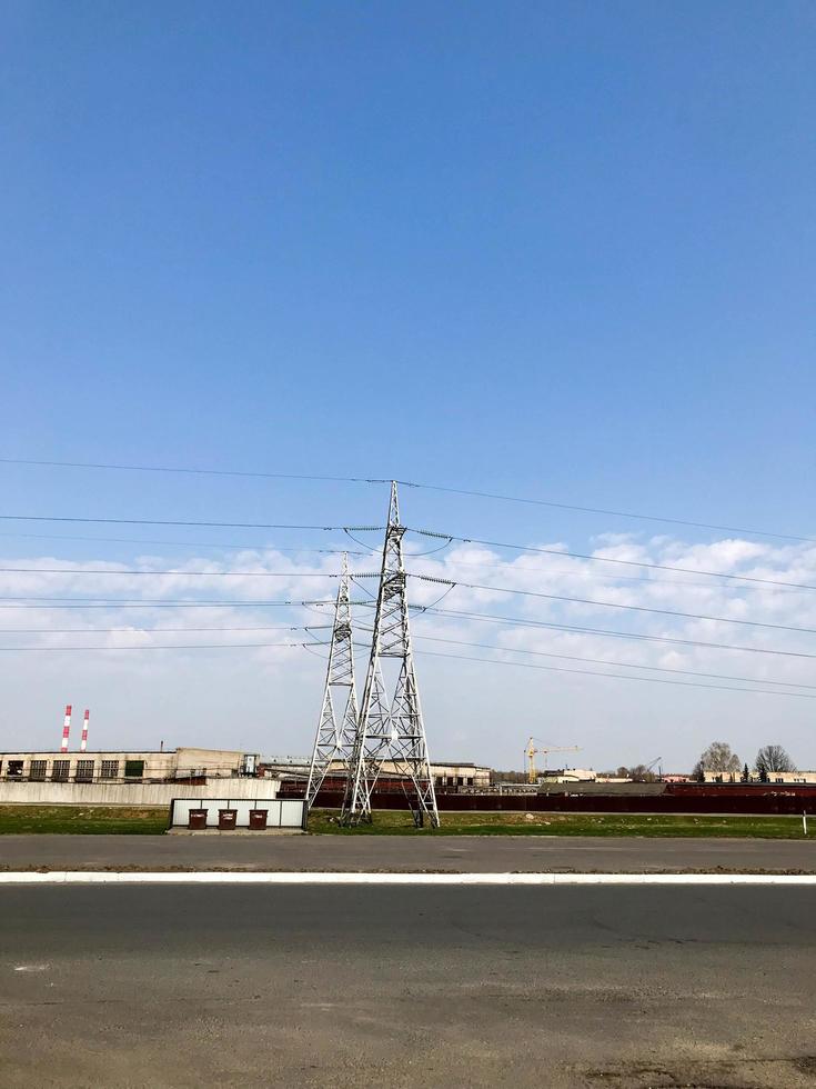 planta de energía con torres y cables de alto voltaje de metal alto, pilares contra el fondo de edificios industriales foto