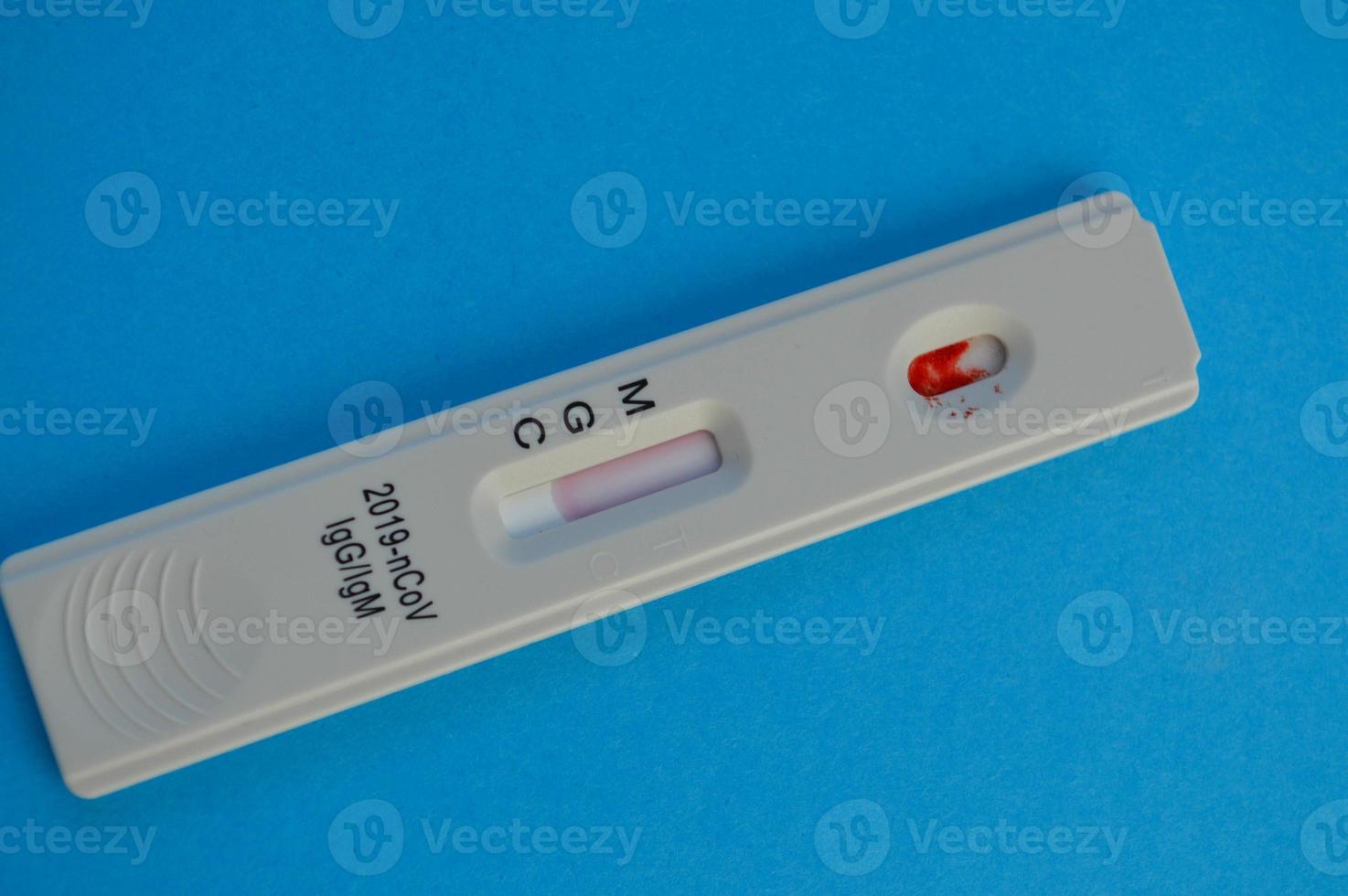coronavirus test lies on a blue background. there is a drop of blood on the test strip. express diagnostics of coronavirus. home test to diagnose infection photo