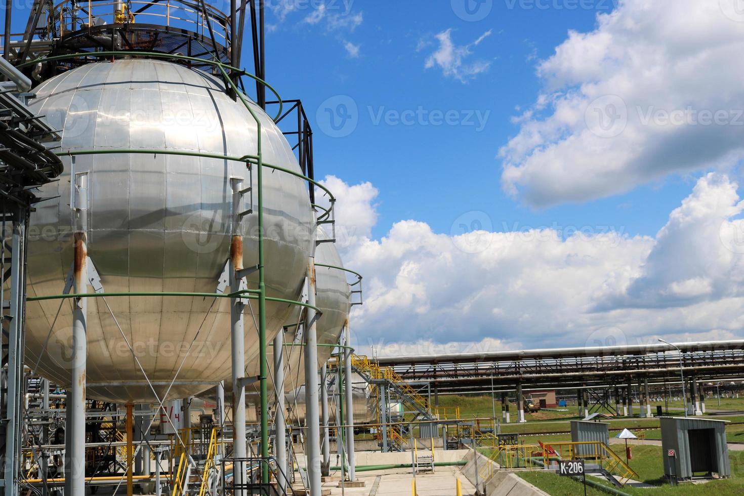 A large round ball-shaped shiny metallic high-pressure iron storage tank for ammonia is strong with pipes and equipment at the petrochemical chemical refinery industrial refinery photo