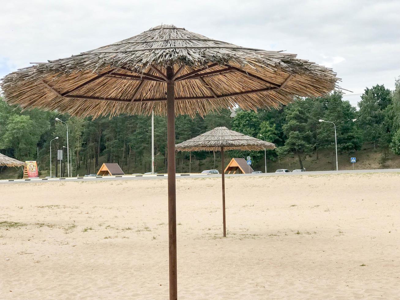 An empty deserted beach in bad weather, cold autumn in the off-season with thatched sun umbrellas against the blue sky photo