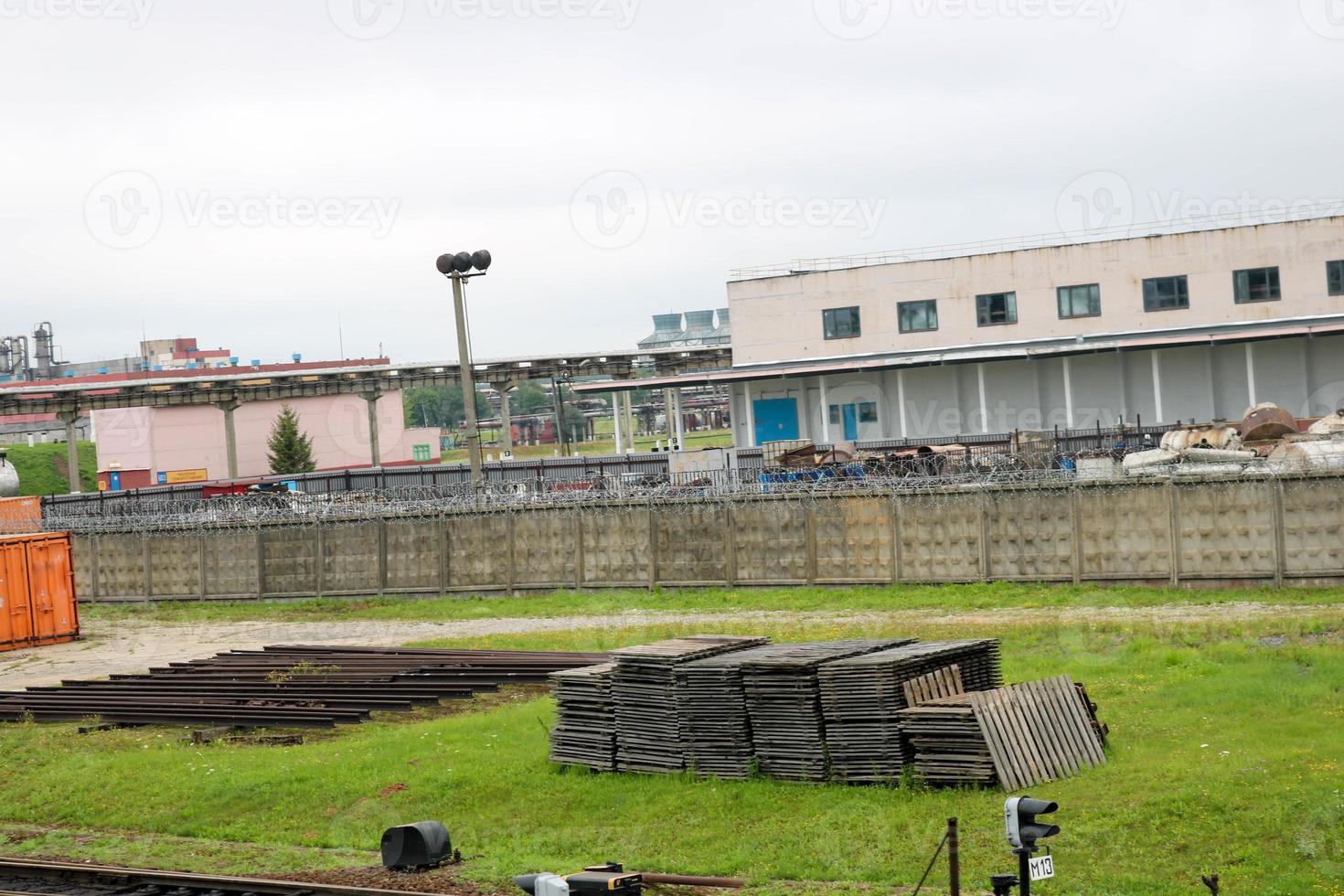 un montón de palets de madera yacen almacenados en el césped de la calle bajo el cielo abierto en una planta industrial foto