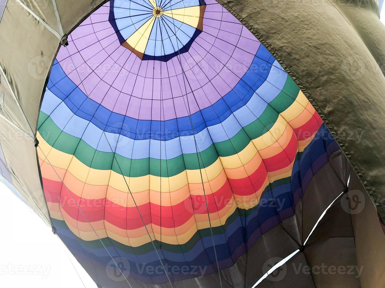 The texture, the view from the inside of the dome is a large multi-colored bright round iridescent colored striped flying balloon. The background photo