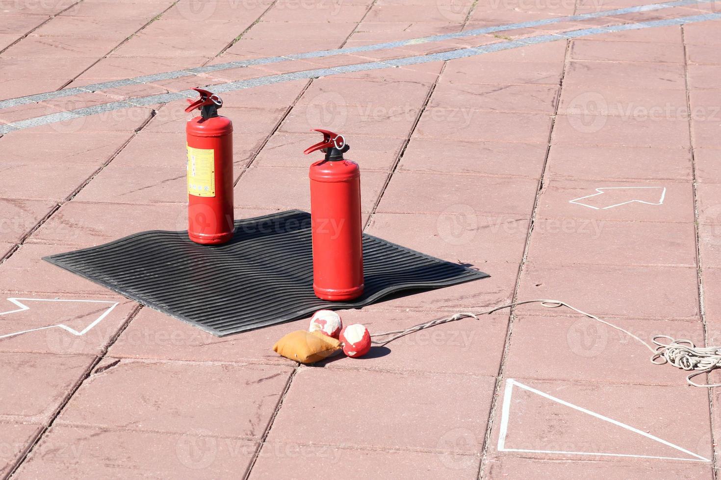 dos grandes extintores manuales de dióxido de carbono o polvo de metal rojo para extinguir un puesto de fuego sobre una alfombra dieléctrica de goma negra en el suelo foto