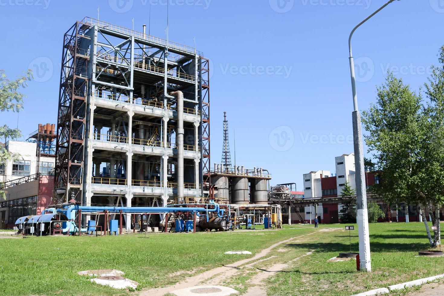A large concrete technological industrial installation at a chemical petrochemical refinery with capacitive pipes by pumps compressors heat exchangers by pipelines and buildings photo