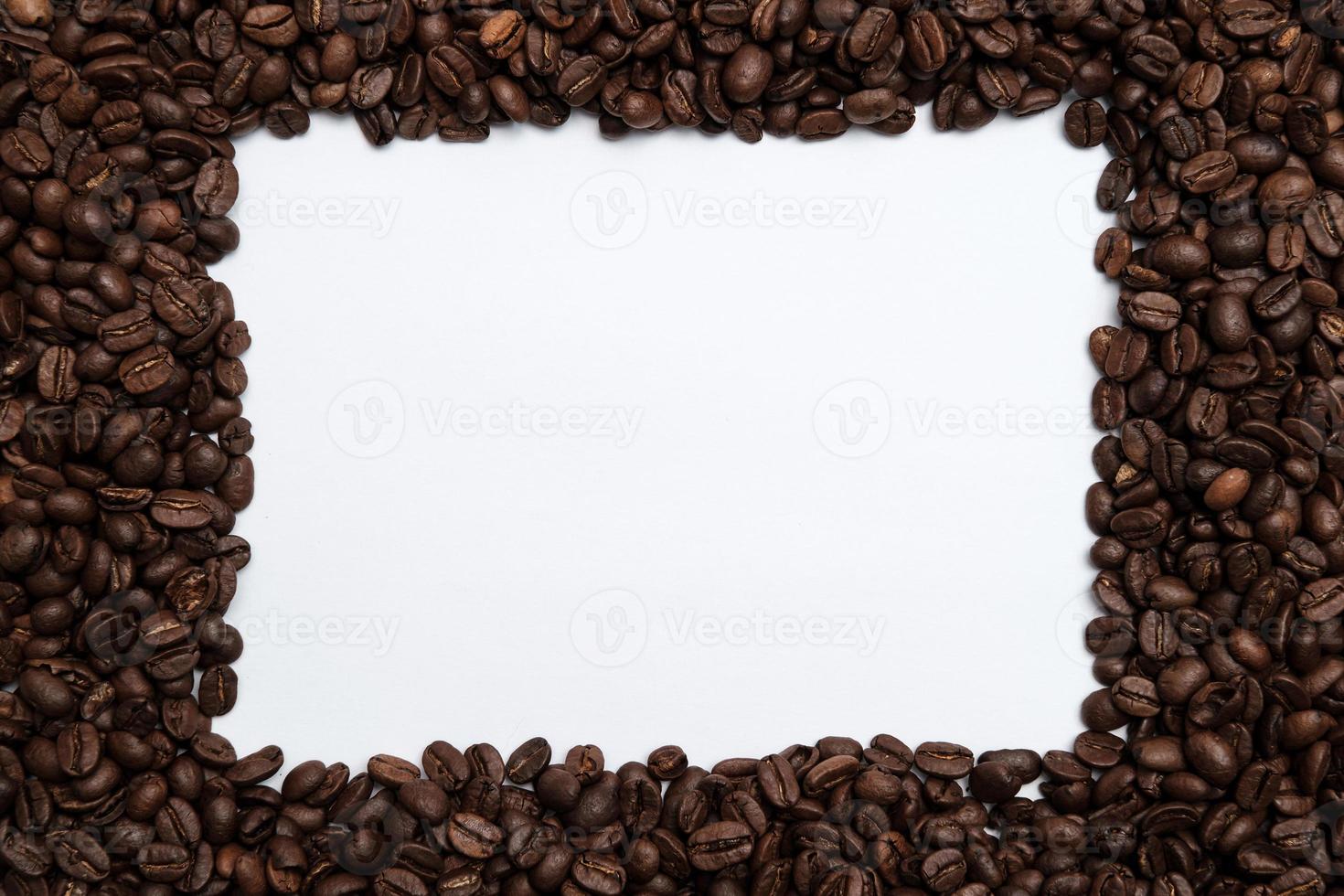 Roasted coffee beans surround a white frame. Copy space. Top view. photo