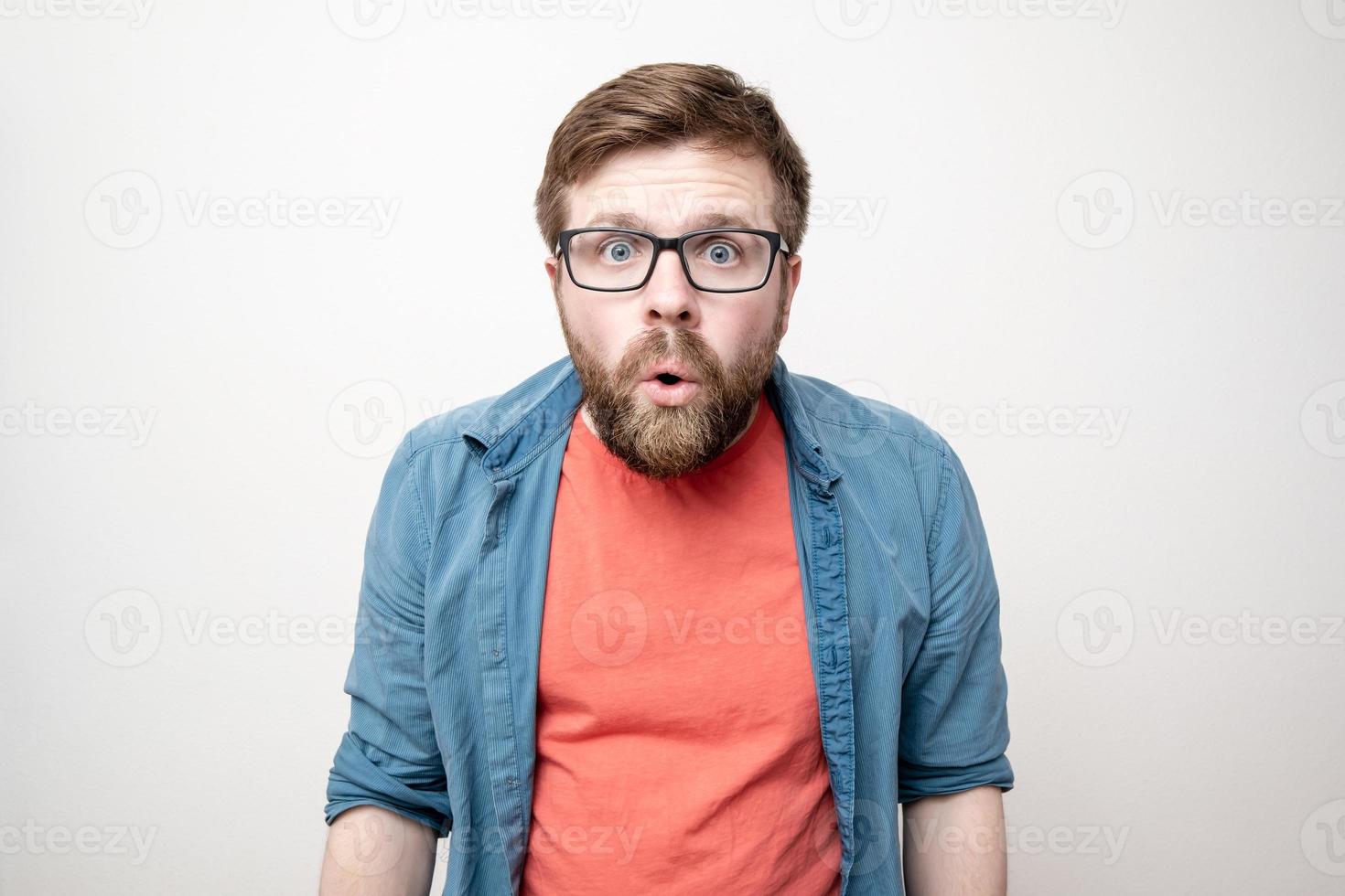 el hombre con gafas mira sorprendido a la cámara con la boca abierta. Fondo blanco. foto