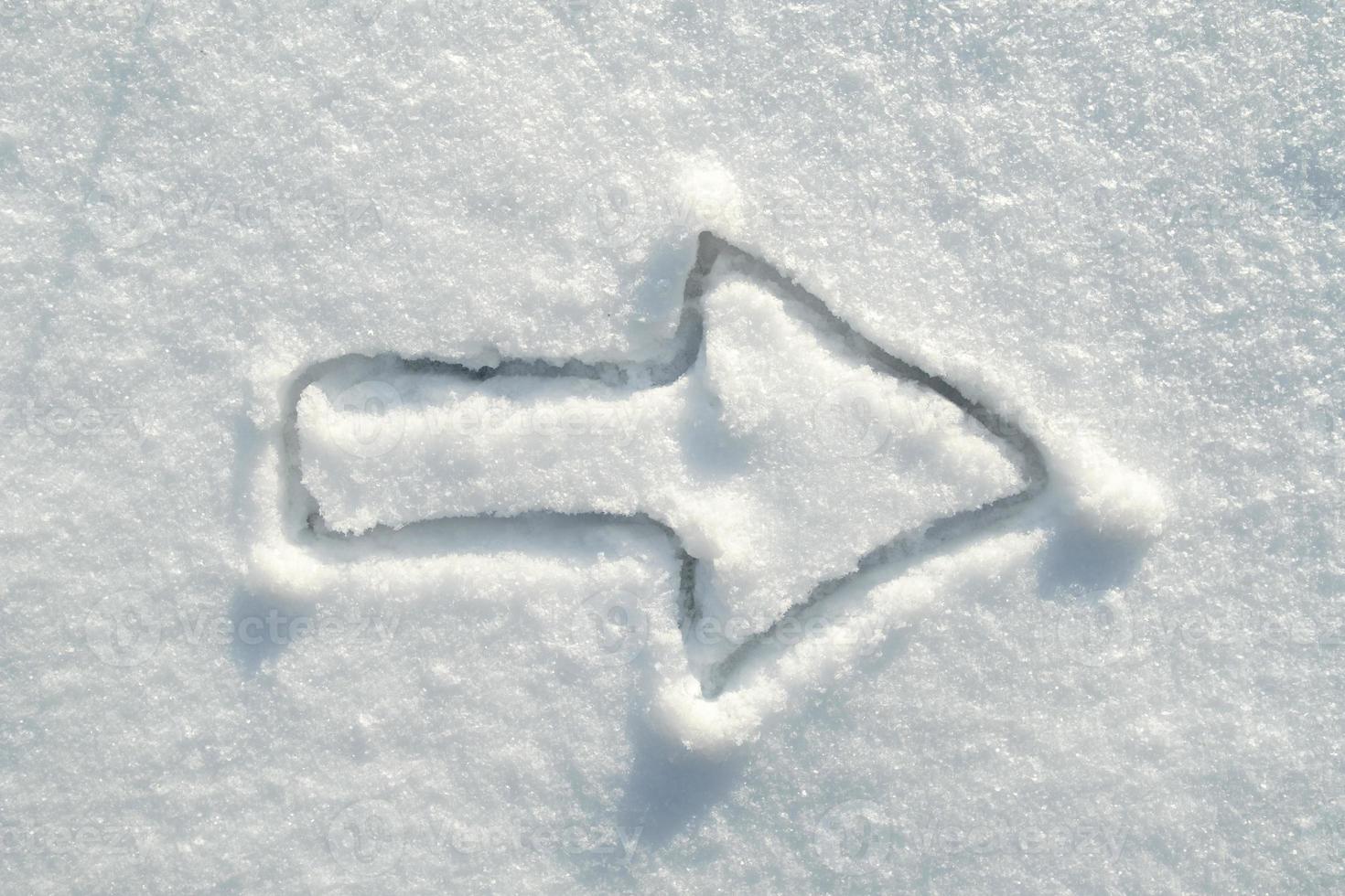 Arrow sign drawing on the snow, on a sunny day. Move to the right. Copy space. Top view. photo