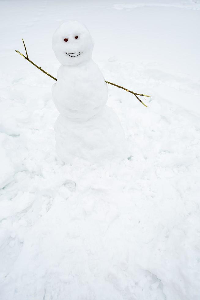 A cute homemade snowman smiles and wants a hug, against a background of pure snow. Traditional winter fun. photo