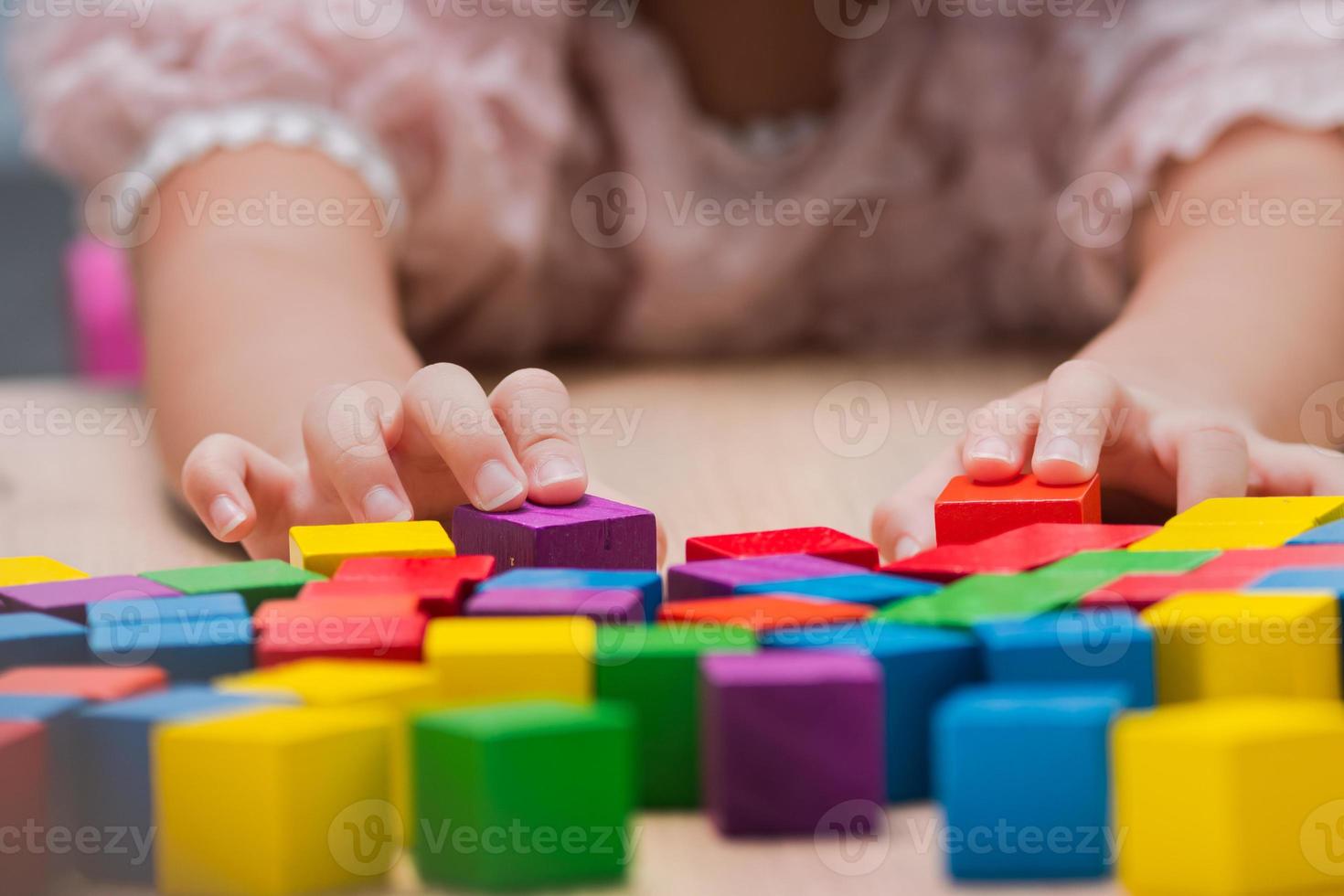 Chica de mano de primer plano jugando colorido juguete de bloque de madera en la mesa para creativo con disfrute. el niño feliz aprende habilidades para el rompecabezas de actividades y la creatividad para el juego en el escritorio en casa. concepto de educación foto