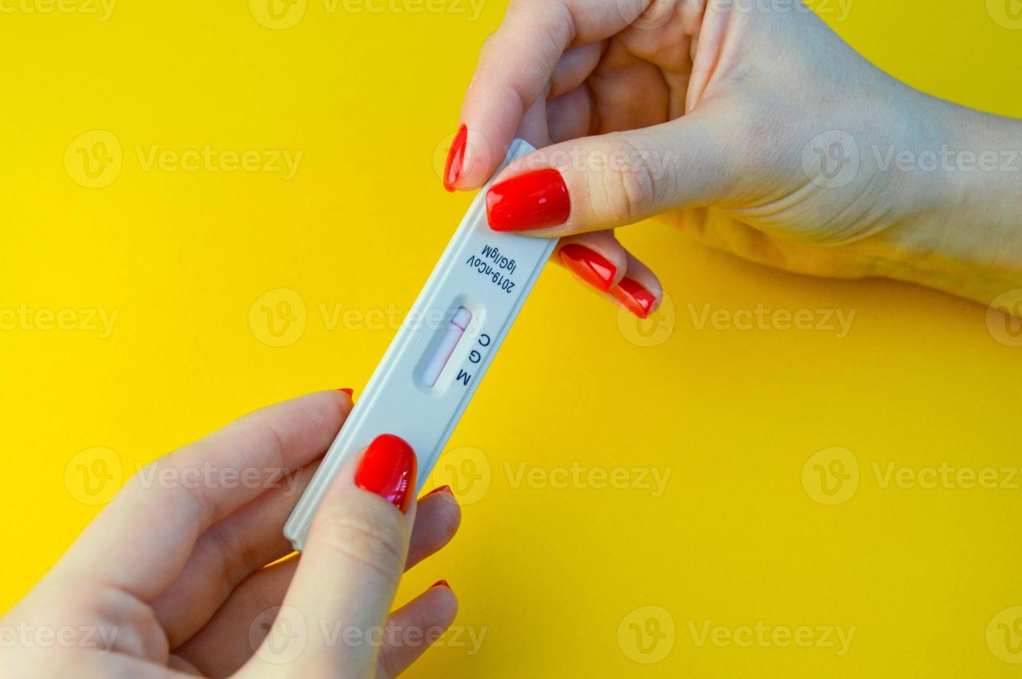 prueba de coronavirus sobre un fondo amarillo y brillante. análisis médico. chica con manicura roja brillante con una prueba negativa de anticuerpos contra el coronavirus foto