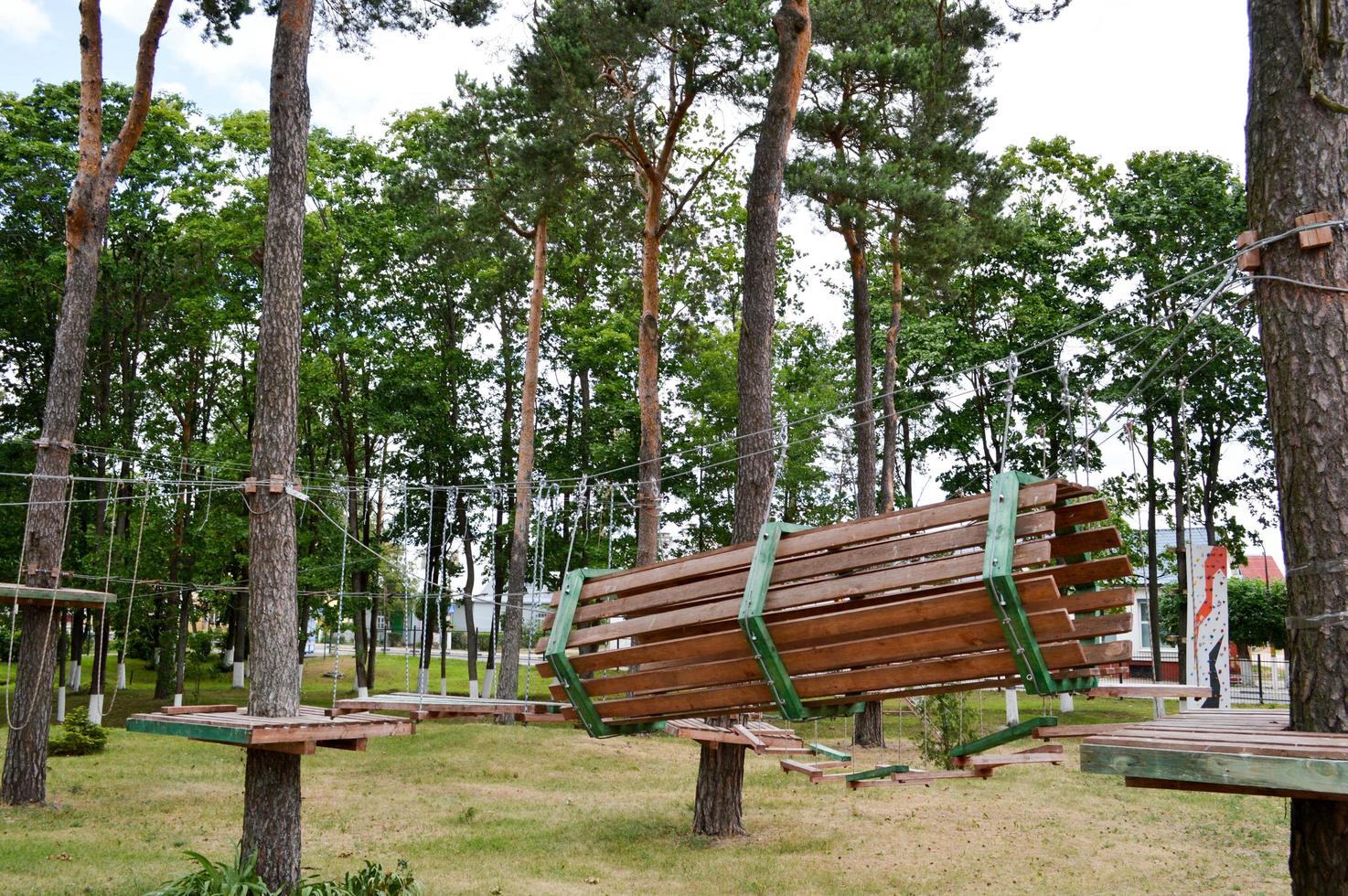 A climbing wall, trolls and a rope park are sporting for games and entertainment from boards and trees with ropes for playing children and adults in the woods in nature photo