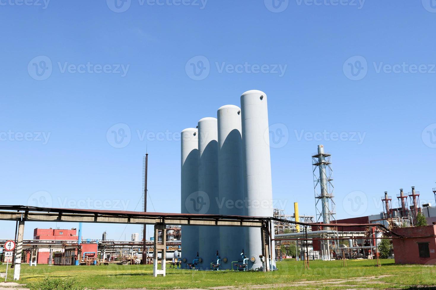 A large concrete technological industrial installation at a chemical petrochemical refinery with capacitive pipes by pumps compressors heat exchangers by pipelines and buildings photo