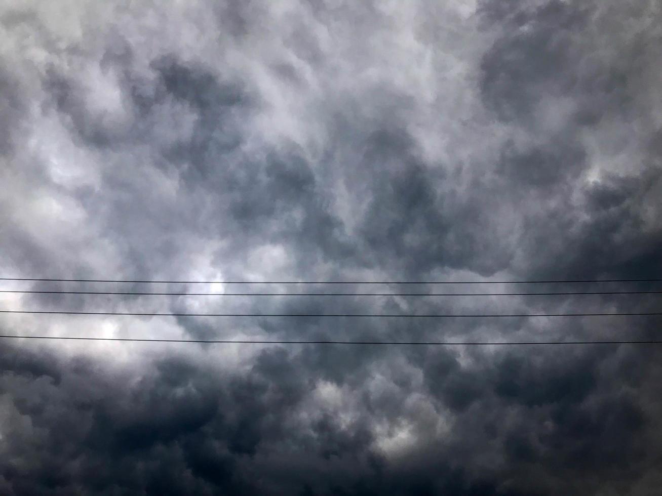 Texture of black tensioned high-voltage wires for electricity against a background of dark blue sullen storm stormy sky with rain clouds photo