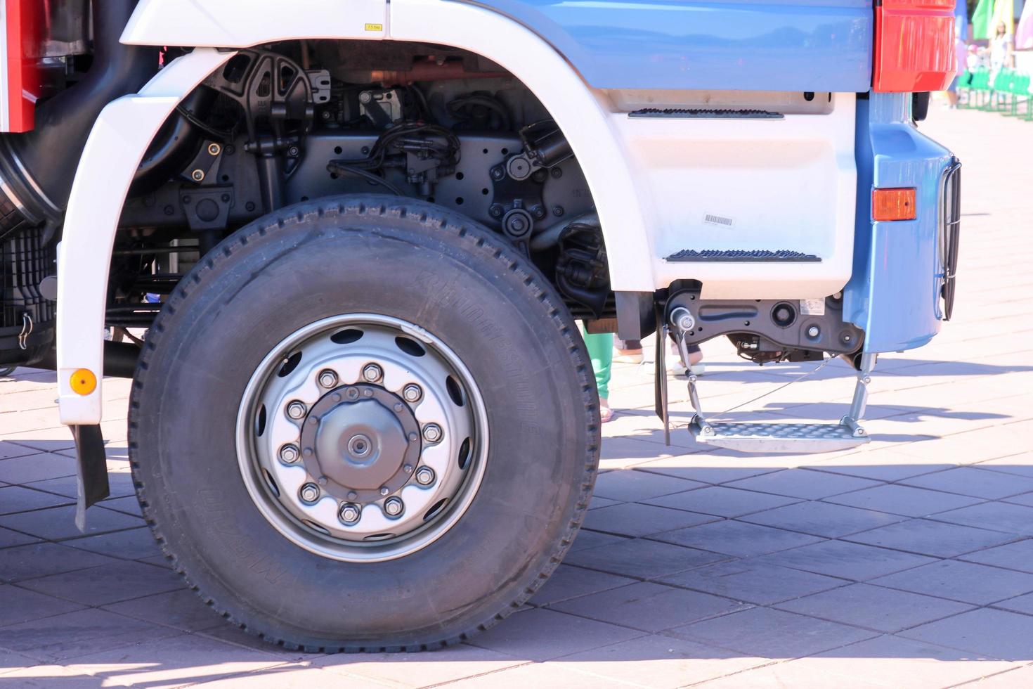 A large black rubber wheel with a truck cover with a metal disk and car suspension elements photo