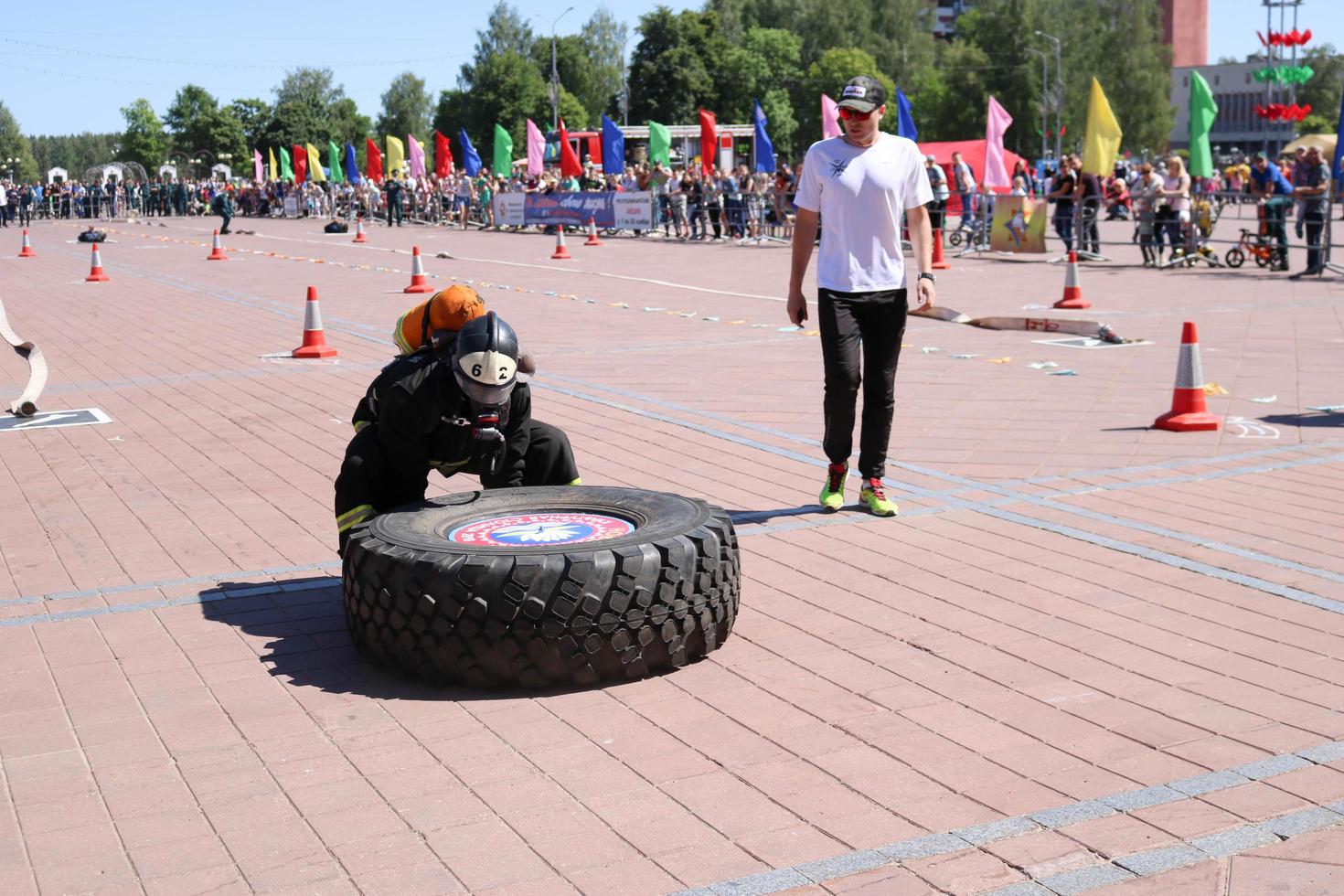 A fireman in a fireproof suit and a helmet runs and turns a large rubber wheel in a fire fighting competition, Belarus, Minsk, 08.08.2018 photo