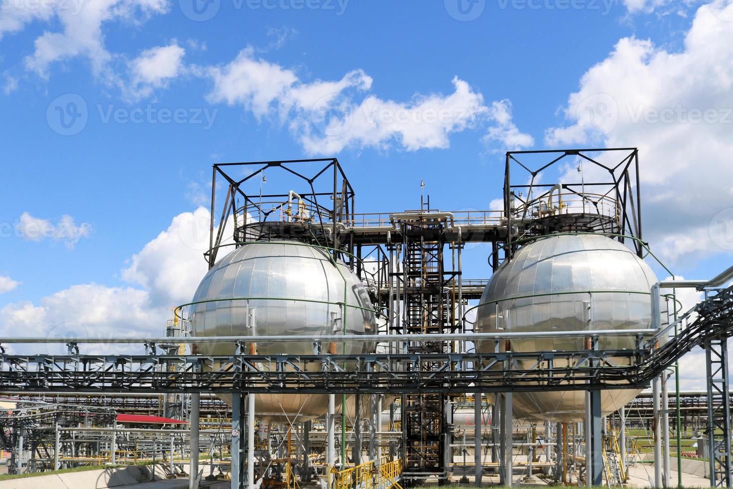 A large round ball-shaped shiny metallic high-pressure iron storage tank for ammonia is strong with pipes and equipment at the petrochemical chemical refinery industrial refinery photo
