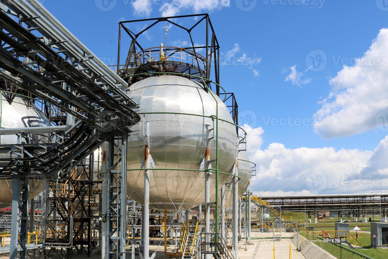 A large round ball-shaped shiny metallic high-pressure iron storage tank for ammonia is strong with pipes and equipment at the petrochemical chemical refinery industrial refinery photo