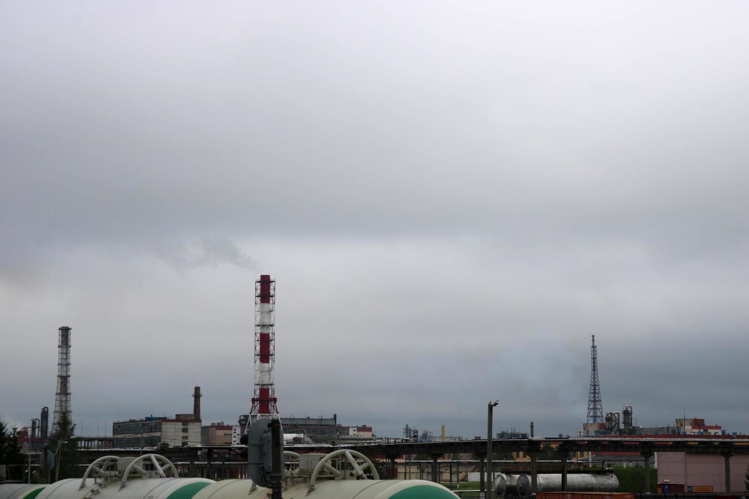 A large high non-ecological metallic iron pipe for the emission of smoke gas at the petrochemical chemical refinery industrial refinery against the background of the blue sky photo