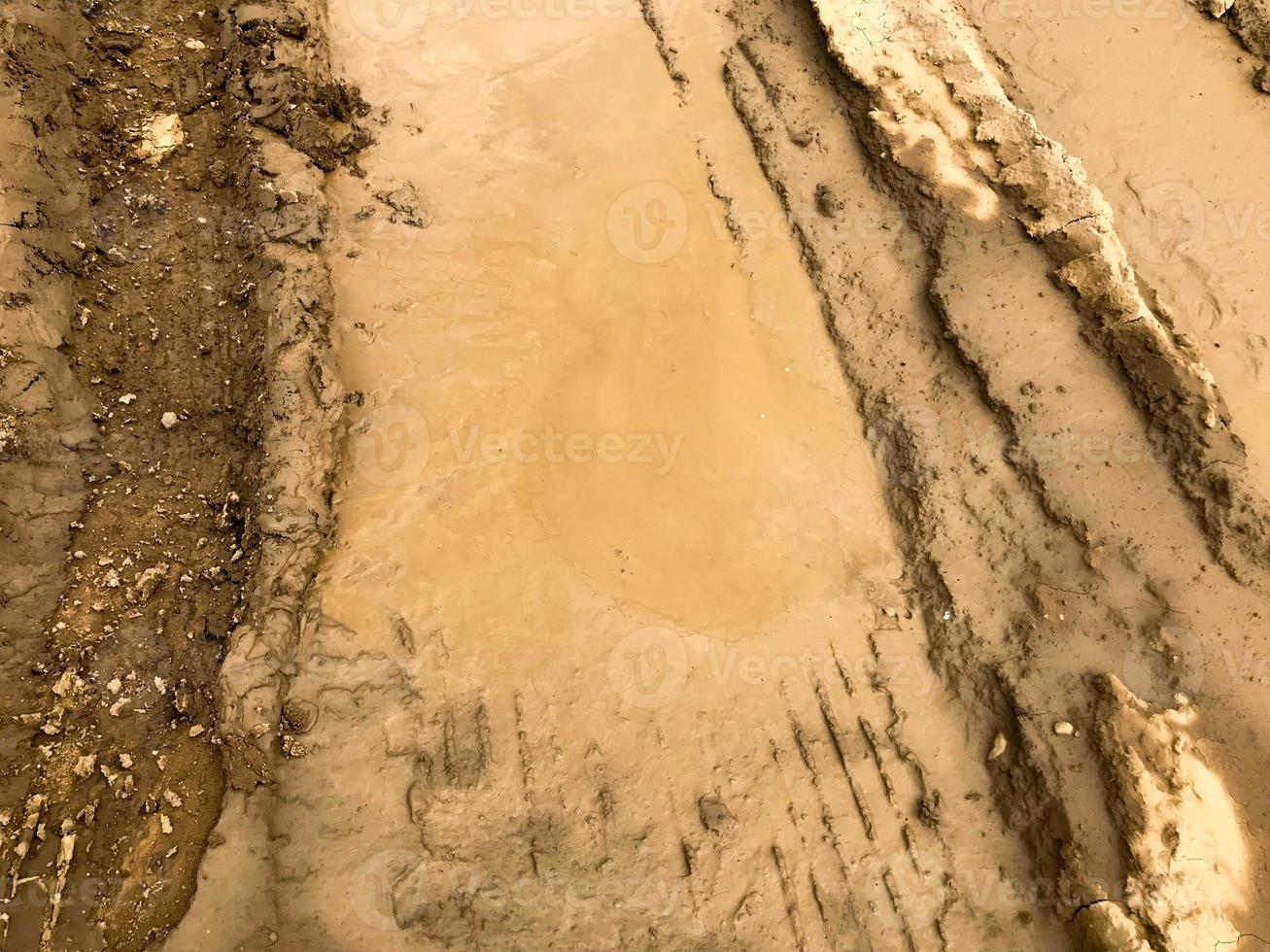Texture of a dirty bad dirt road dirt road with puddles and clay drying mud with cracks and ruts. Off-road. The background photo