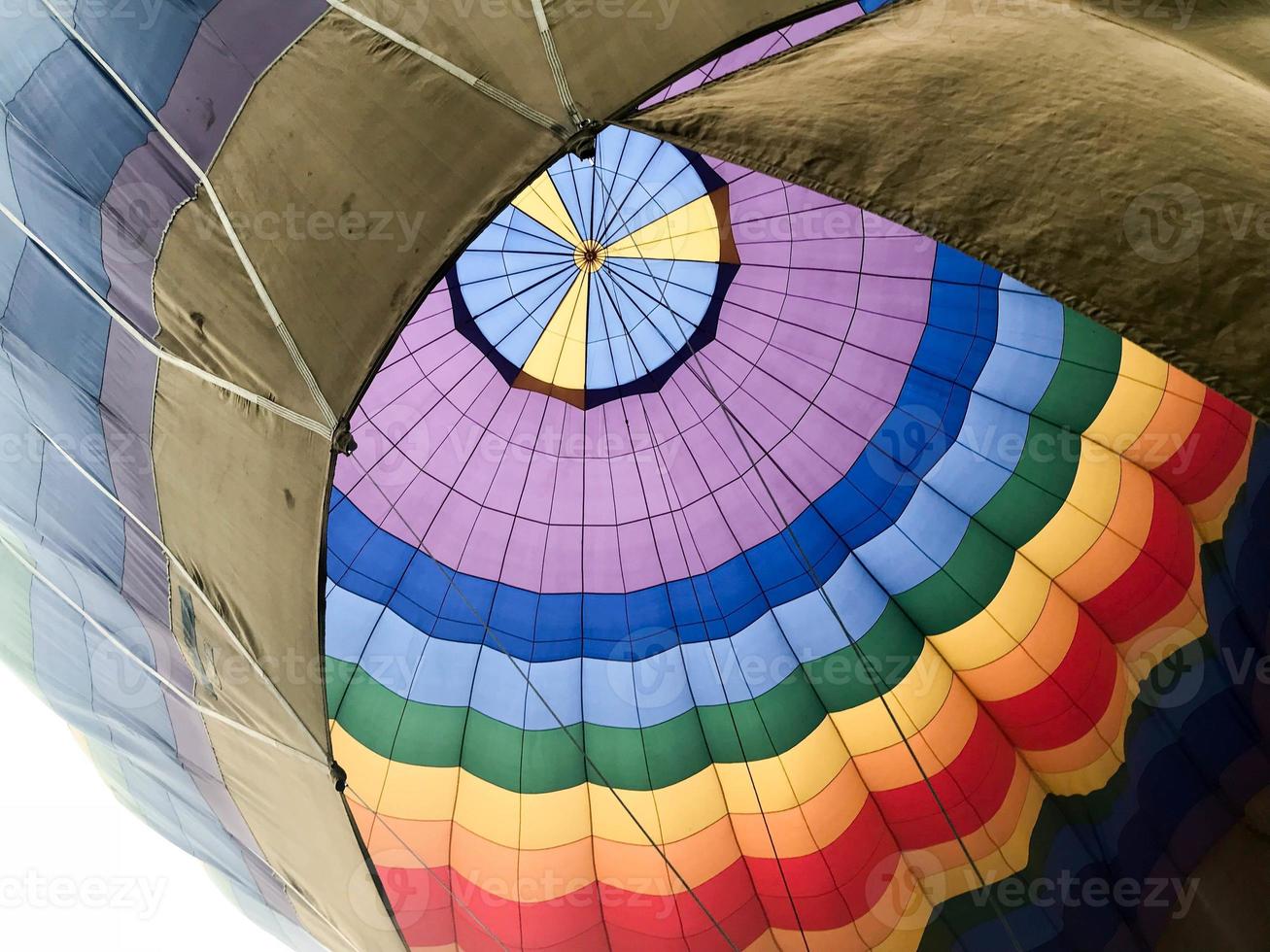 The texture, the view from the inside of the dome is a large multi-colored bright round iridescent colored striped flying balloon. The background photo