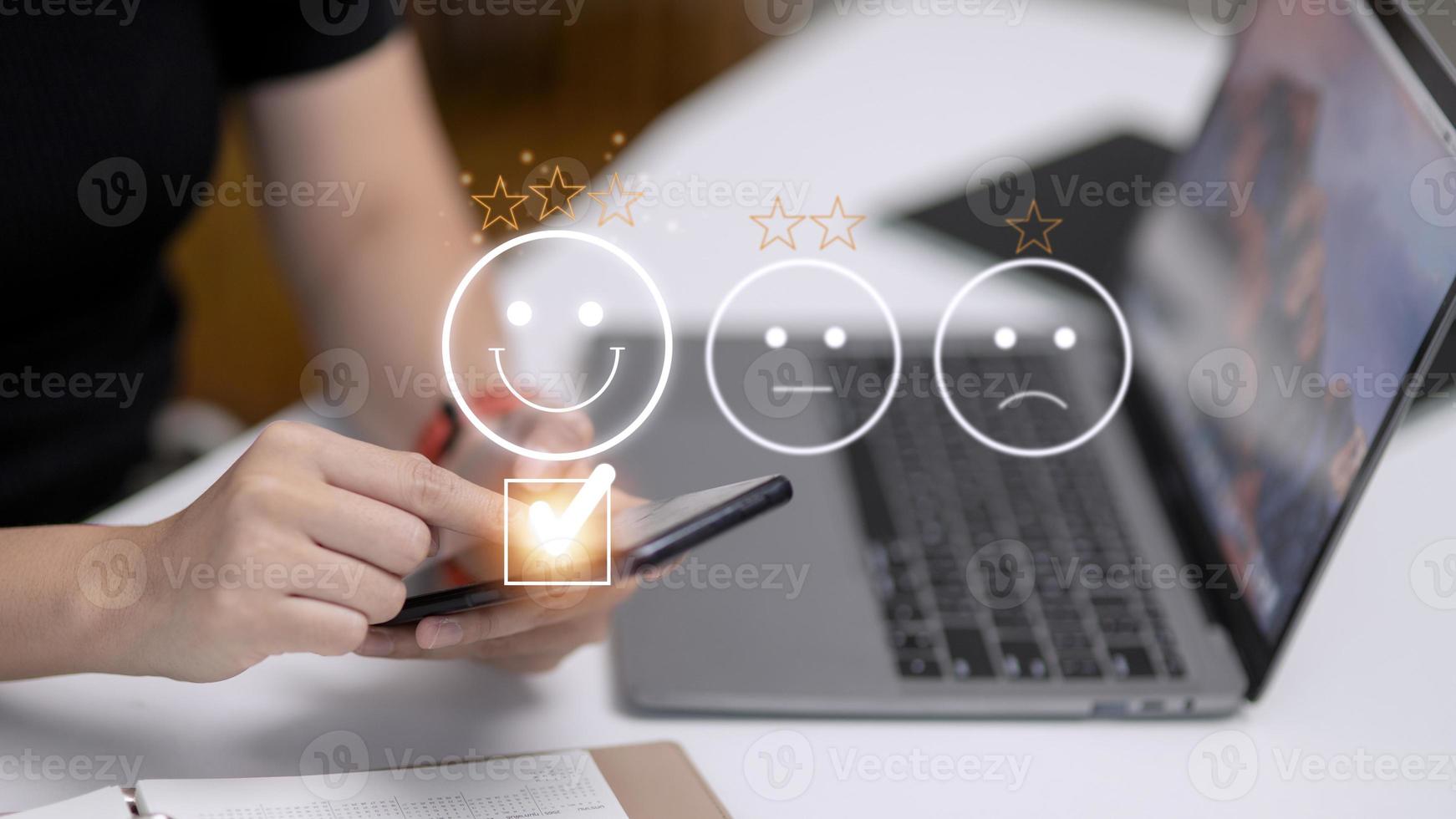 Customer service evaluation concept. using a smartphone is pressing face emoticon smiling in satisfaction on virtual touch screen. photo