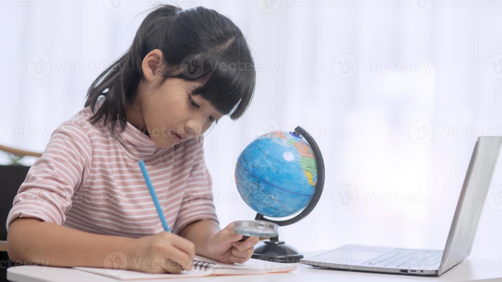 Asian little girl is learning the globe model, concept of save the world and learn through play activity for kid education at home. photo