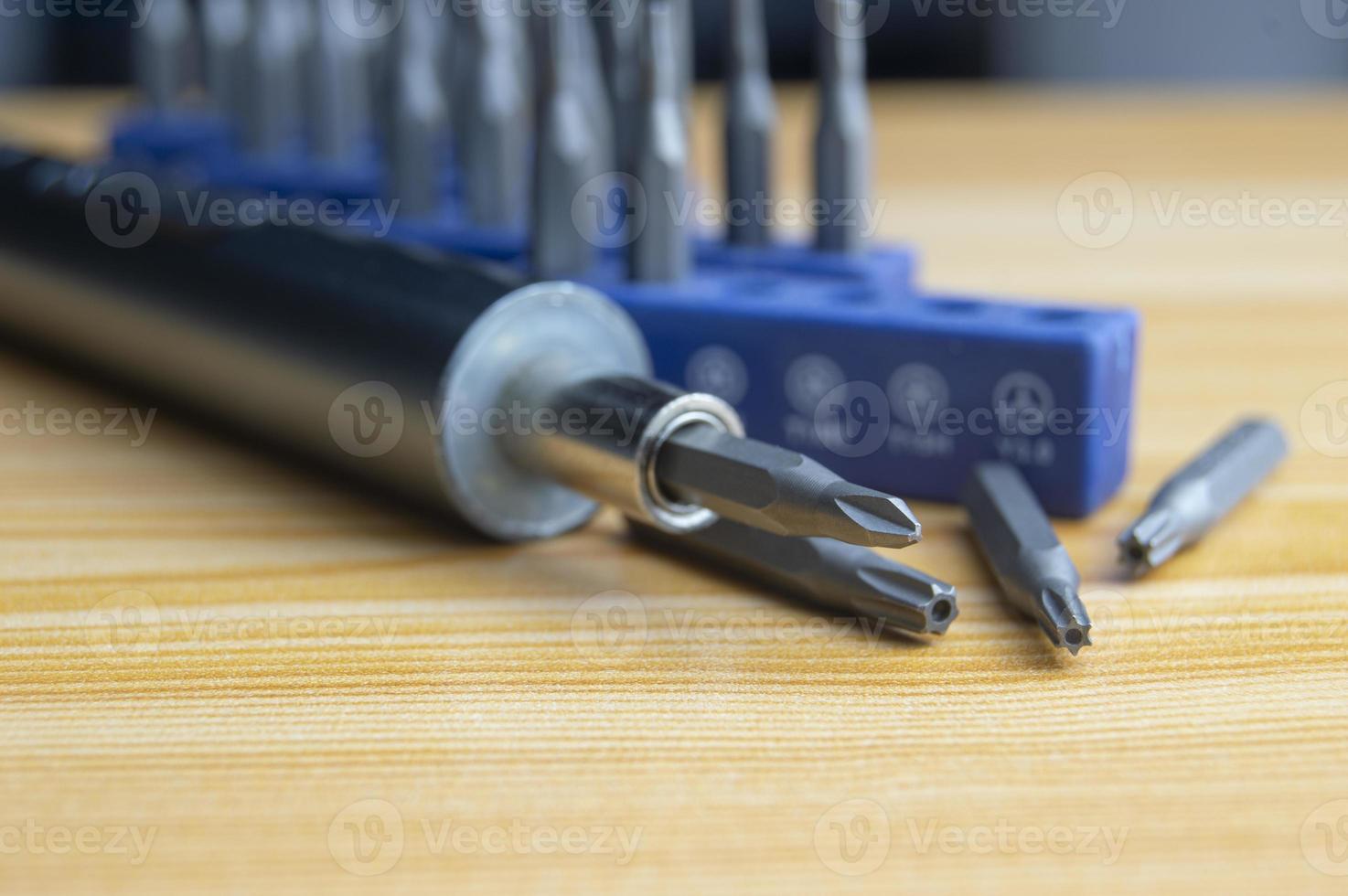 Picture of a mini electric screwdriver, interchangeable tip, placed on a wooden floor. photo