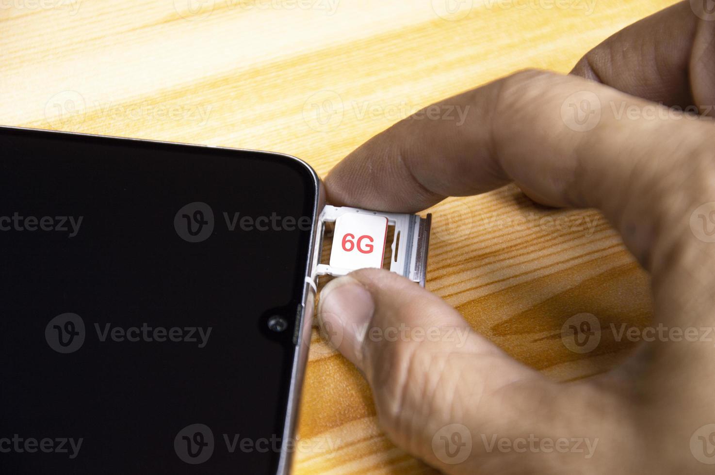 6G technology, Internet concept. SIM card in smartphone tray on wooden table, closeup 6G network concept, high speed mobile internet New age network, business concept photo