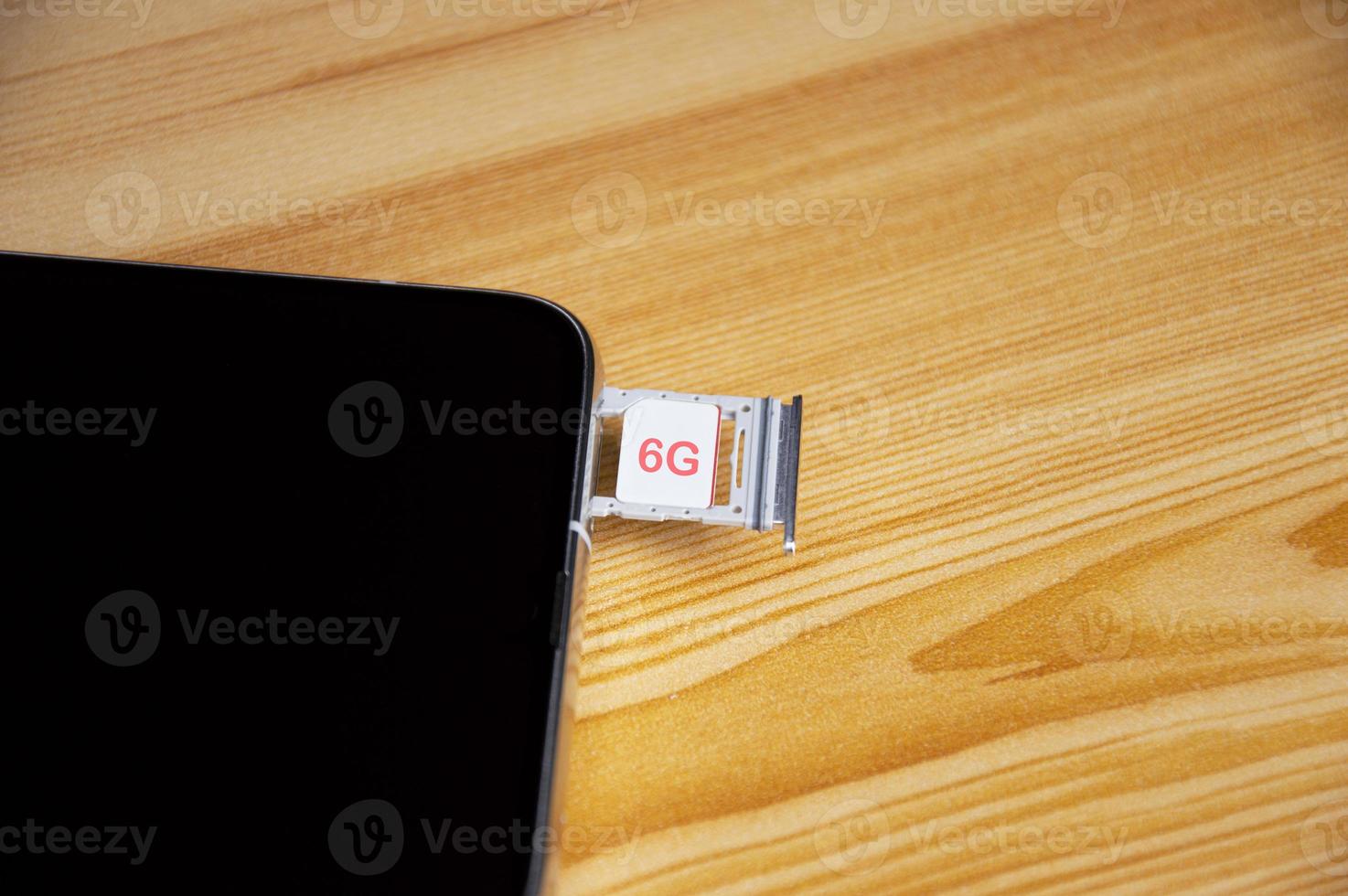 6G technology, Internet concept. SIM card in smartphone tray on wooden table, closeup 6G network concept, high speed mobile internet New age network, business concept photo