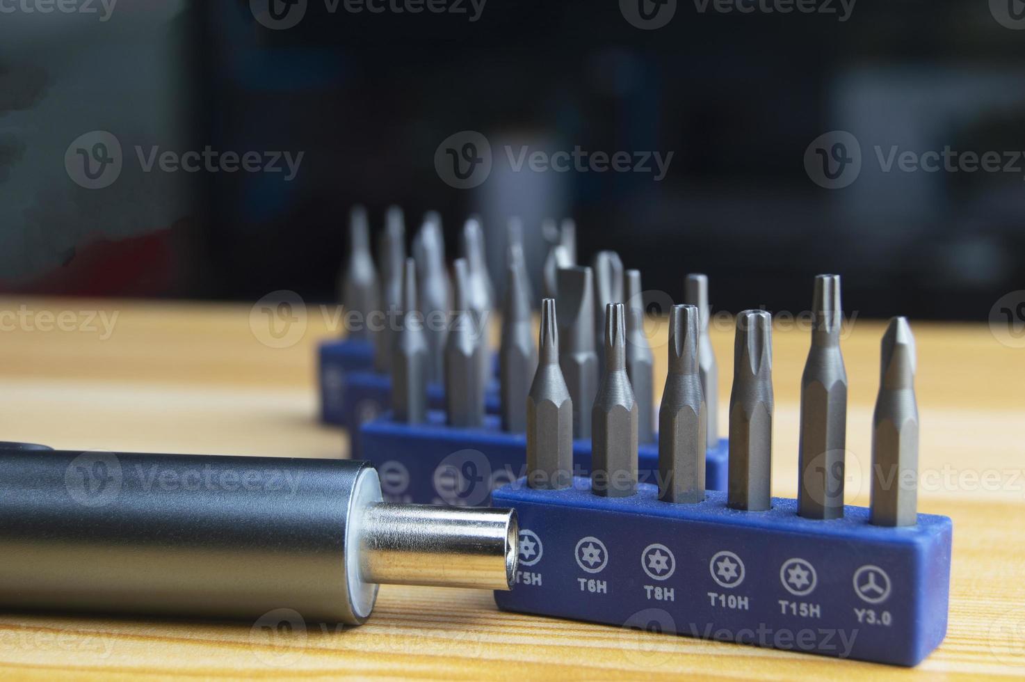 Picture of a mini electric screwdriver, interchangeable tip, placed on a wooden floor. photo