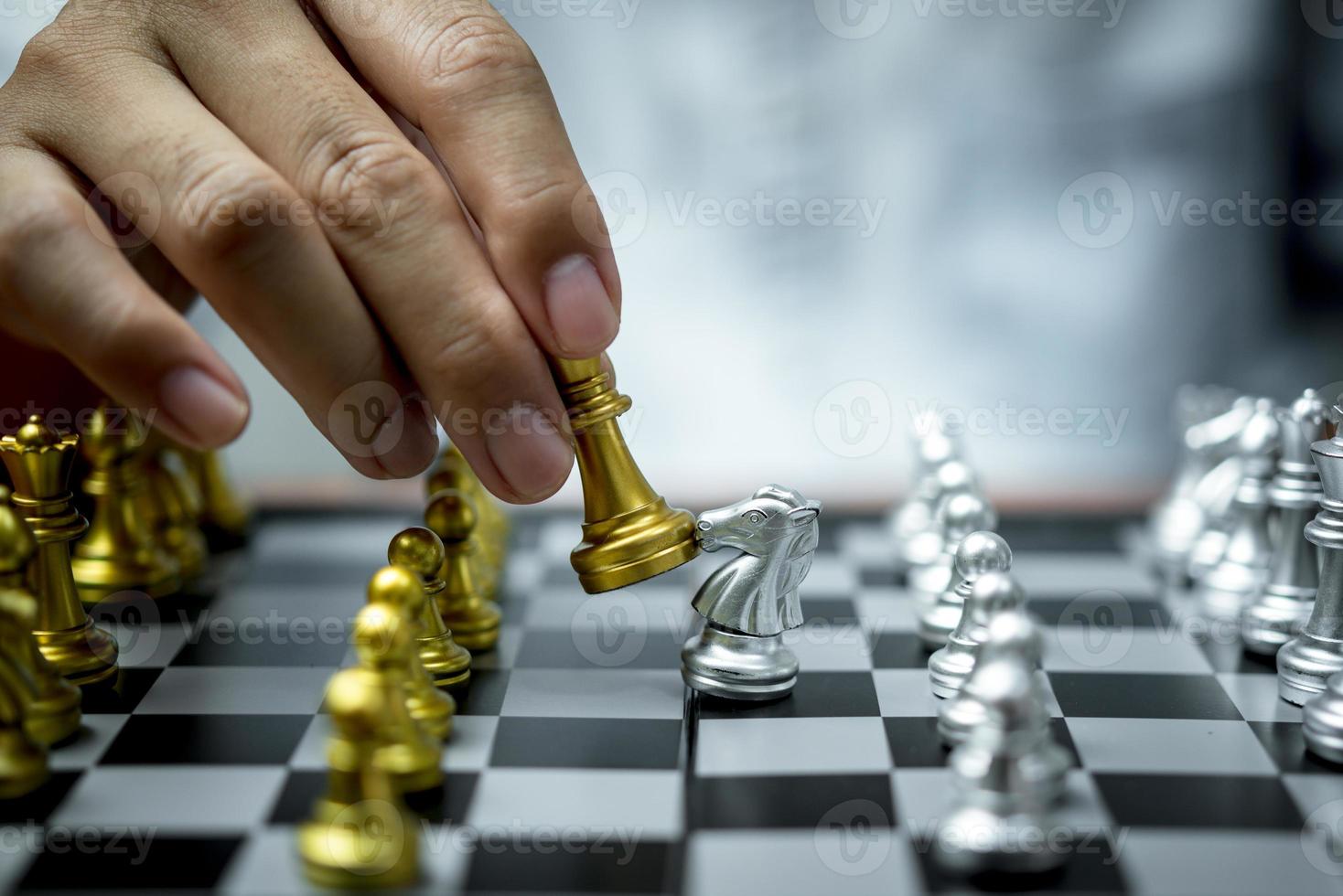 Close up of hands of a business man moving king golden chess to defeat  opponent the chess game is development analysis, strategy, and plan, the  management or leadership concept. 22804709 Stock Photo