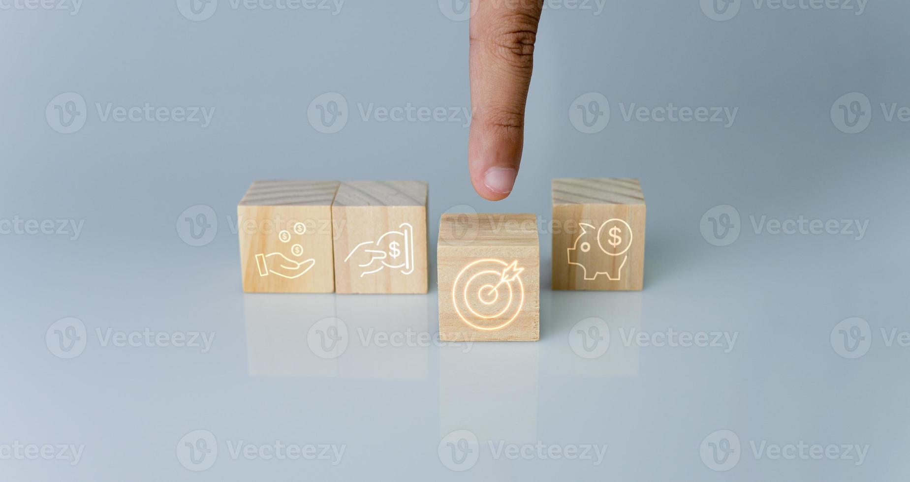 Hand pointing at one wood cube block with target icon . Concept of business strategy and goal action plan. photo
